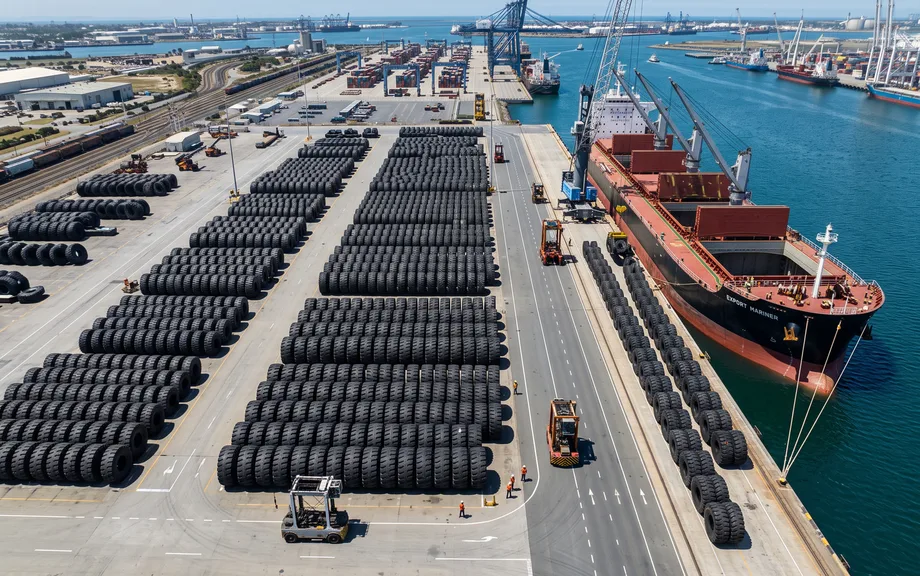Giant tires lined up on a port quay next to a cargo ship